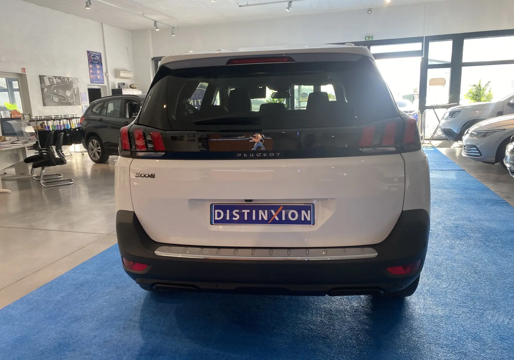 Vue arrière d'un Peugeot 5008 blanc Blanquise dans un showroom, avec plaque Distinxion visible.