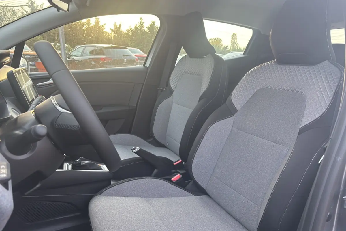 Intérieur de la Renault Clio 2025, vue côté gauche sur les sièges avant gris avec surpiqûres et volant.