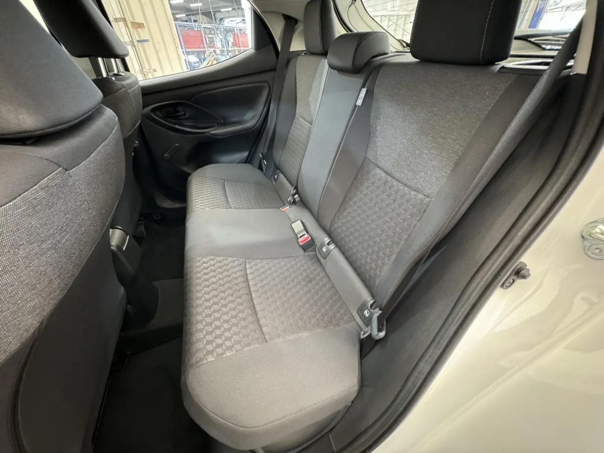 Vue intérieure côté droit des sièges arrière gris de la Toyota Yaris hybride blanche 2022 avec porte ouverte.