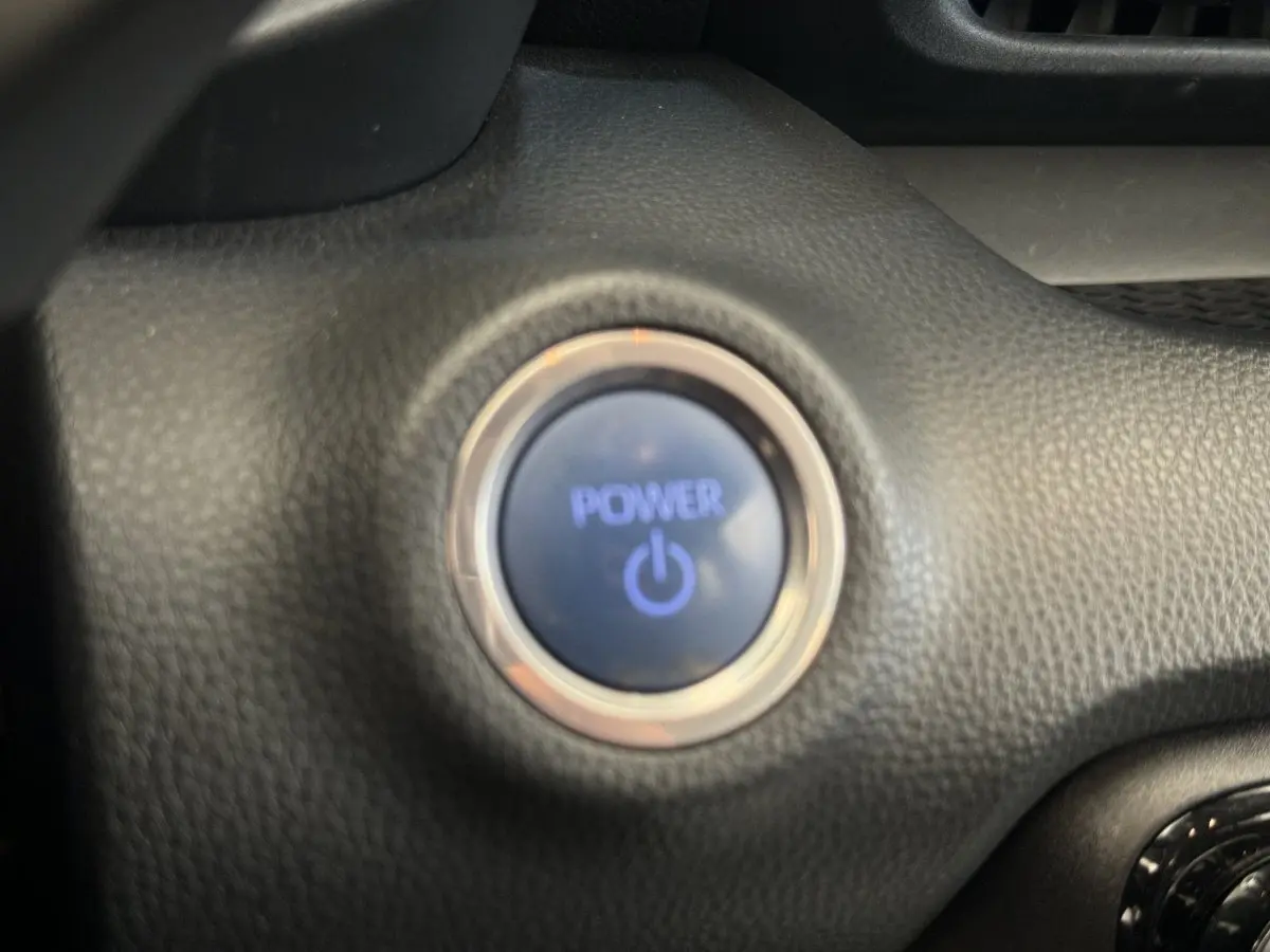 Bouton démarrage Power éclairé en bleu sur tableau de bord noir de la Toyota Yaris hybride 2022.