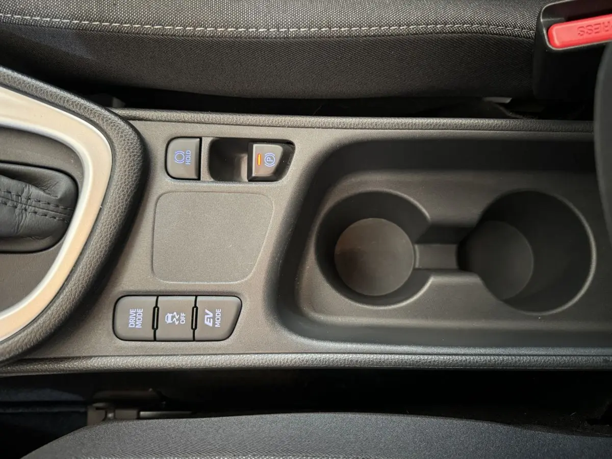 Vue rapprochée de la console centrale noire de la Toyota Yaris hybride 2022, avec boutons de mode de conduite et porte-gobelets.