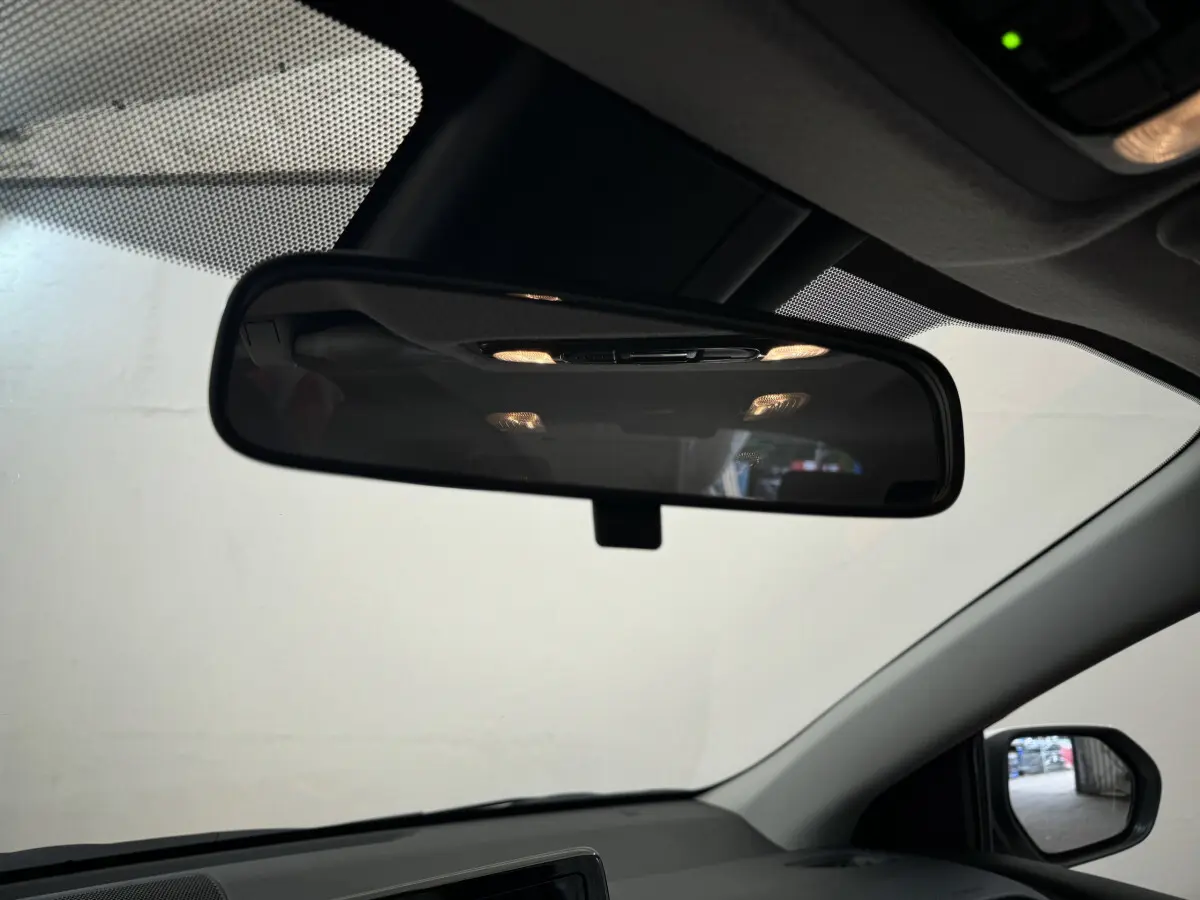 Vue intérieure centrée sur le rétroviseur intérieur de la Toyota Yaris hybride blanche, avec partie du tableau de bord visible.