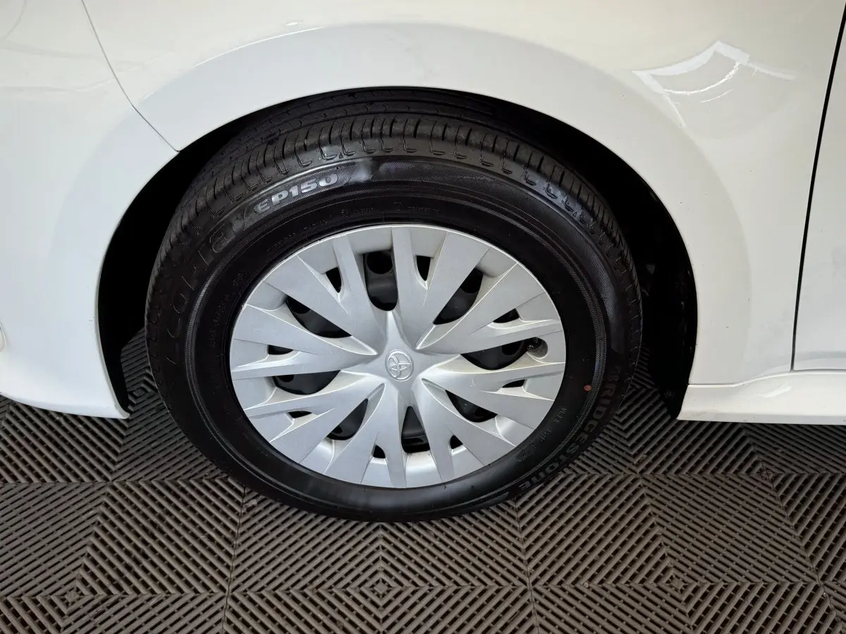 Gros plan sur la roue arrière droite blanche d'une Toyota Yaris hybride 2022 avec enjoliveur argenté et pneu Bridgestone.