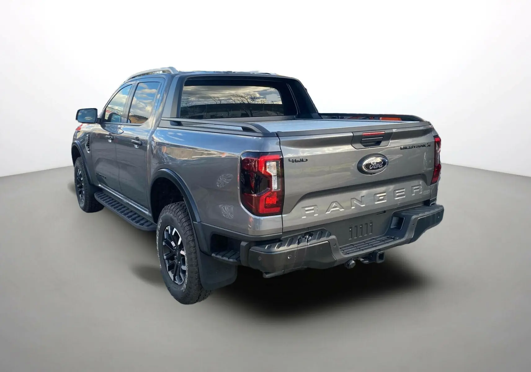 Ford Ranger gris carbone vu en 3/4 arrière droit, avec benne couverte et jantes noires distinctives.