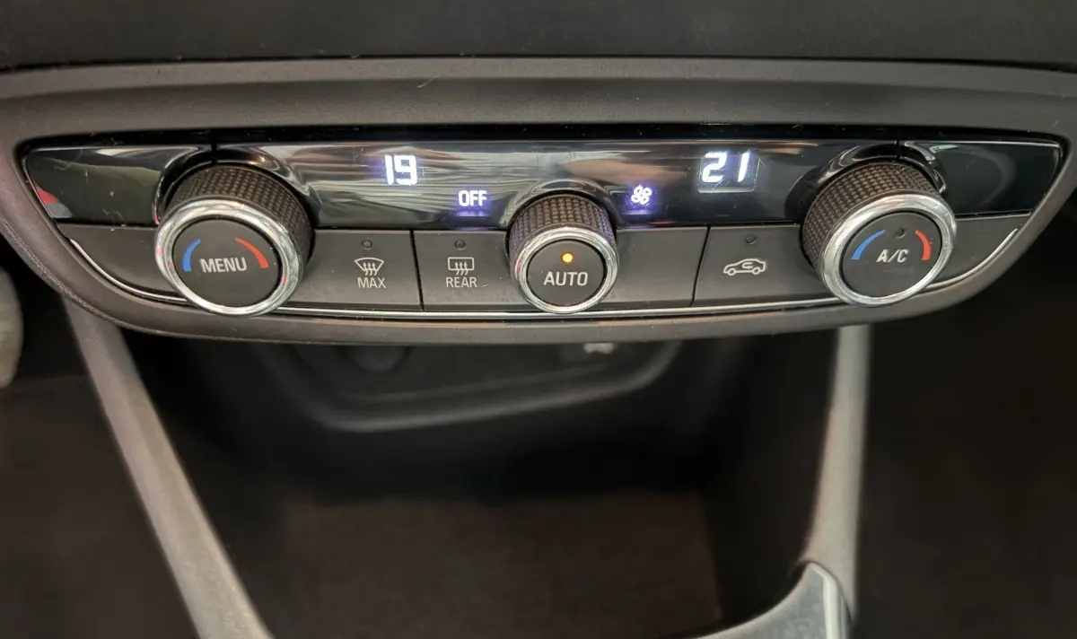 Gros plan sur la commande de climatisation 2 zones de l’Opel Crossland blanc, avec affichage digital et boutons rotatifs.