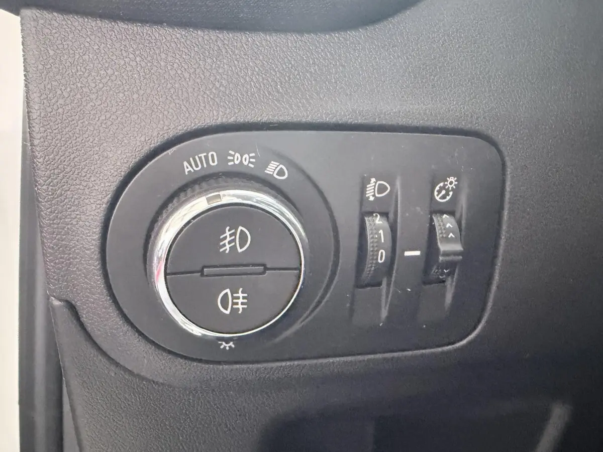 Gros plan sur les commandes d’éclairage intérieures noires de l’Opel Crossland blanc, avec sélecteur rotatif et réglages.