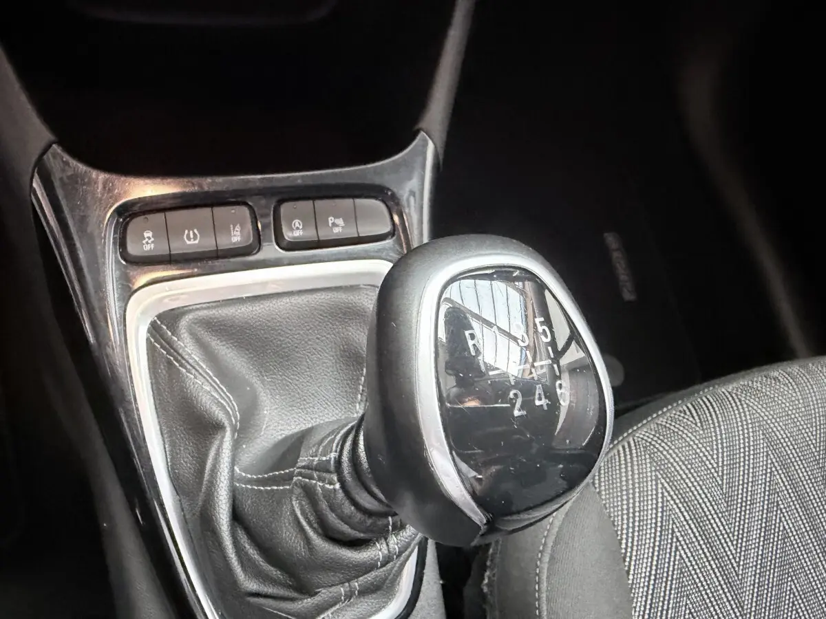 Gros plan sur le levier de vitesses manuel noir et chrome de l’Opel Crossland 1.2 Turbo Elegance, avec boutons de contrôle à proximité.