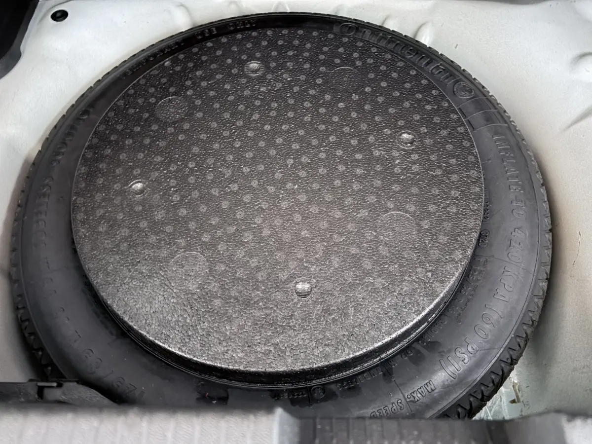 Gros plan sur la roue de secours noire dans le coffre blanc d’un Opel Crossland 2021.