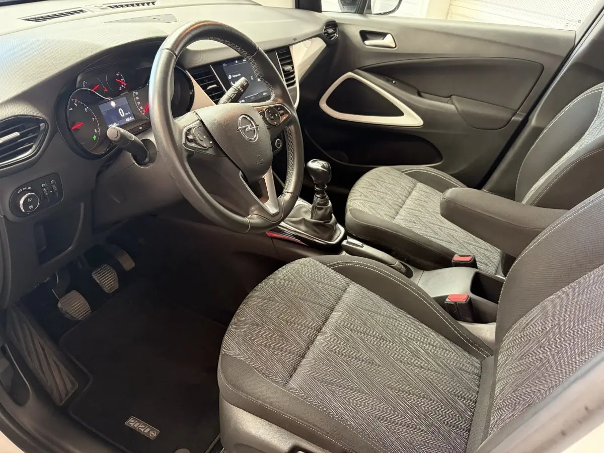 Vue intérieure côté conducteur de l'Opel Crossland 2021, volant cuir alu multifonctions et sièges tissu gris.