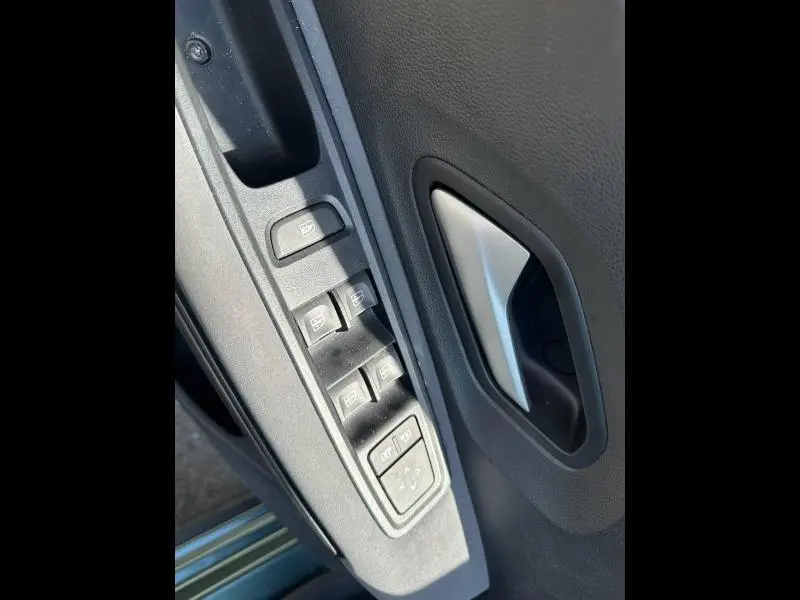Gros plan sur les commandes des vitres électriques et la poignée intérieure côté gauche d'une Dacia Sandero Vert Cèdre métallisé.