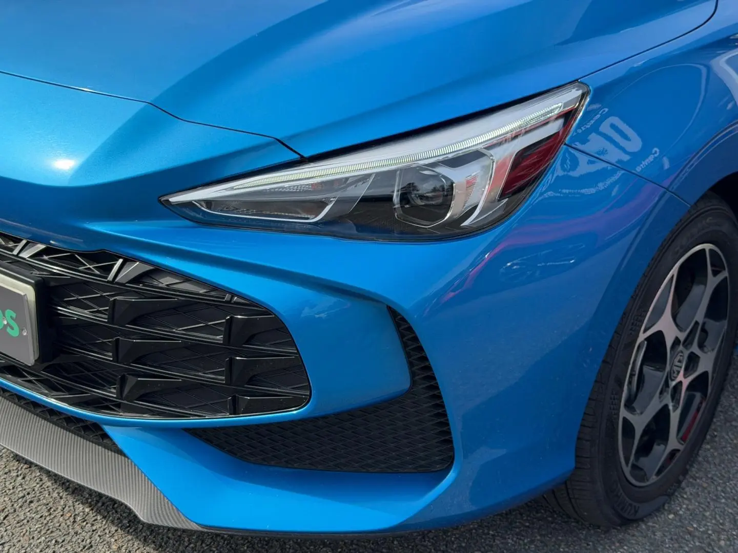 Gros plan sur l'avant droit du MG3 1.5 Hybrid+ 195ch Luxury en Como Blue métallisé avec phare LED et jante alu.