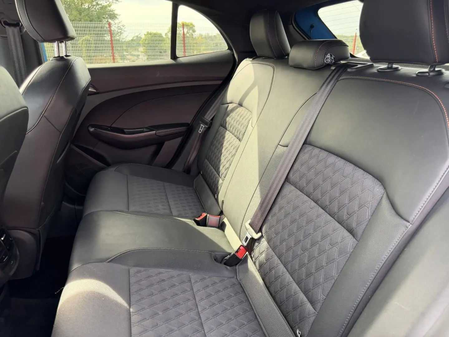 Vue intérieure côté droit des sièges arrière en similicuir noir avec surpiqûres rouges du MG3 1.5 Hybrid+ 195ch Luxury 2025.