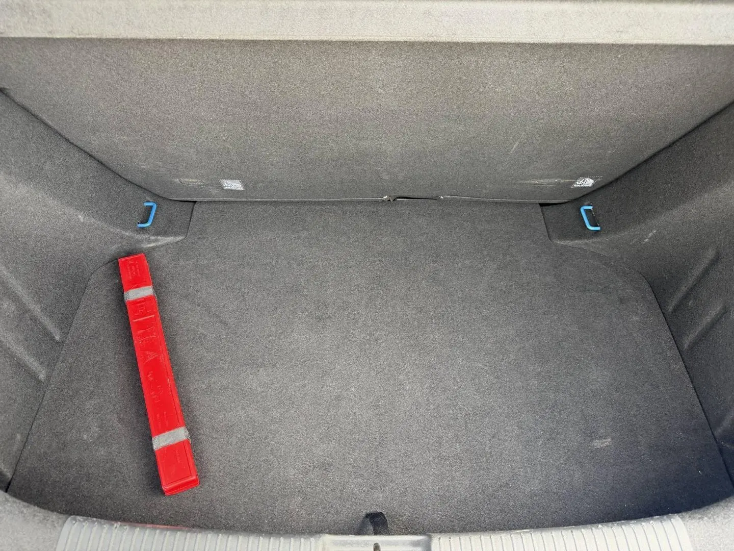 Coffre spacieux de MG3 1.5 Hybrid+ 195ch Luxury, vue intérieure avec tapis gris et triangle de signalisation rouge.