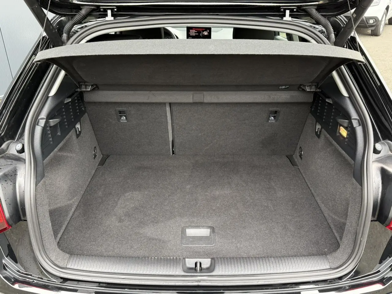 Coffre ouvert vu de l'arrière de l'Audi Q2 35 TFSI S-Line noir Mythe, montrant un plancher plat et un hayon électrique.