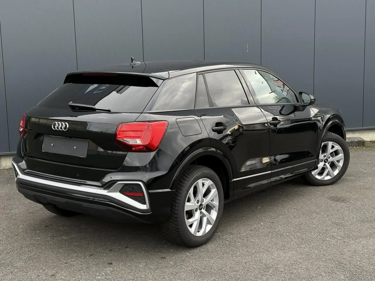 Audi Q2 35 TFSI S-Line noir Mythe vue 3/4 arrière droit, hayon électrique et jantes alliage 17 pouces visibles.