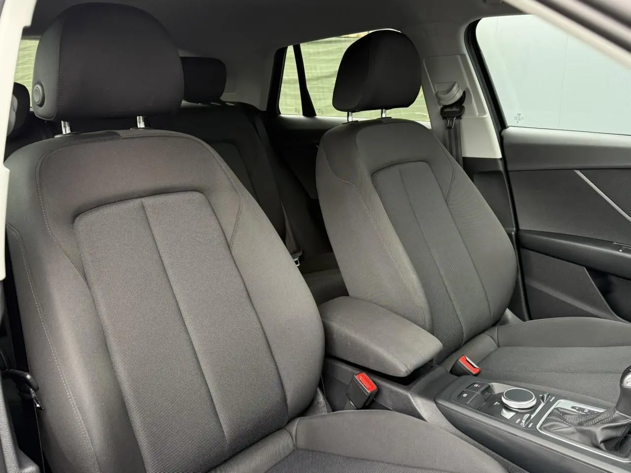 Intérieur de l'Audi Q2 35 TFSI S-Line 2023 montrant les sièges avant en tissu gris et la console centrale.