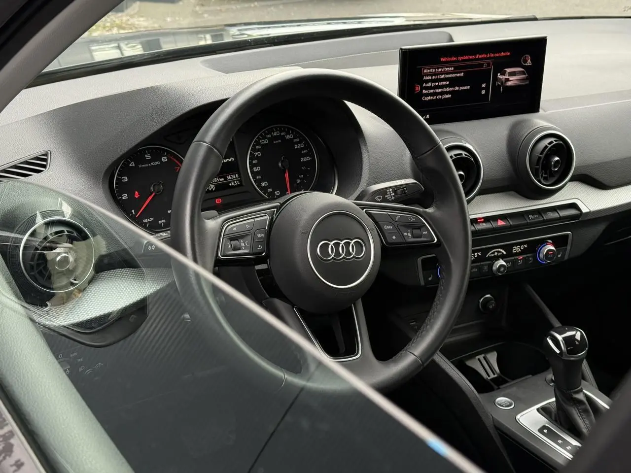 Vue intérieure côté conducteur de l'Audi Q2 35 TFSI 150 S-Tronic S-Line 2023, tableau de bord et volant multifonction.