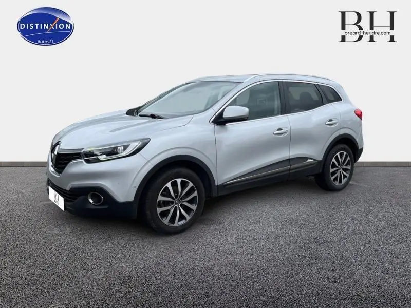Renault Kadjar gris platine vu en 3/4 avant droit, avec jantes alliage et barres de toit noires.
