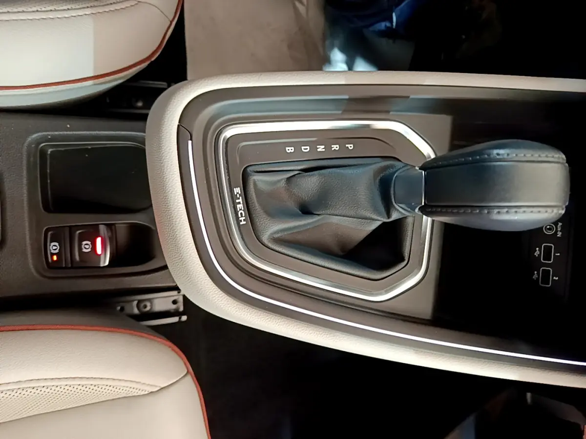 Gros plan sur la console centrale de la Renault Clio Initiale Paris E-TECH 140 avec levier de vitesses automatique et sellerie beige.