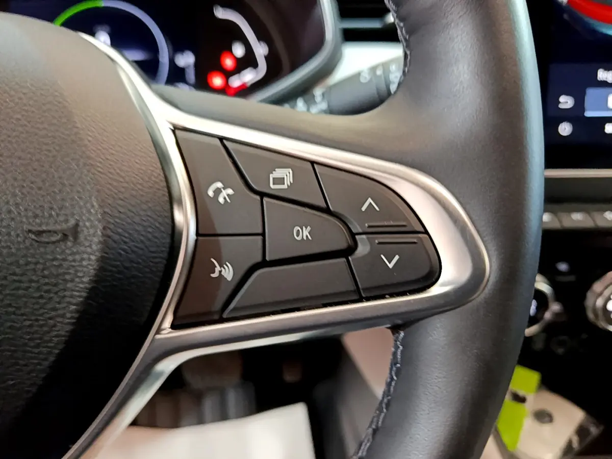 Gros plan sur les commandes au volant droit en cuir noir de la Renault Clio Initiale Paris E-TECH 140 orange 2021.