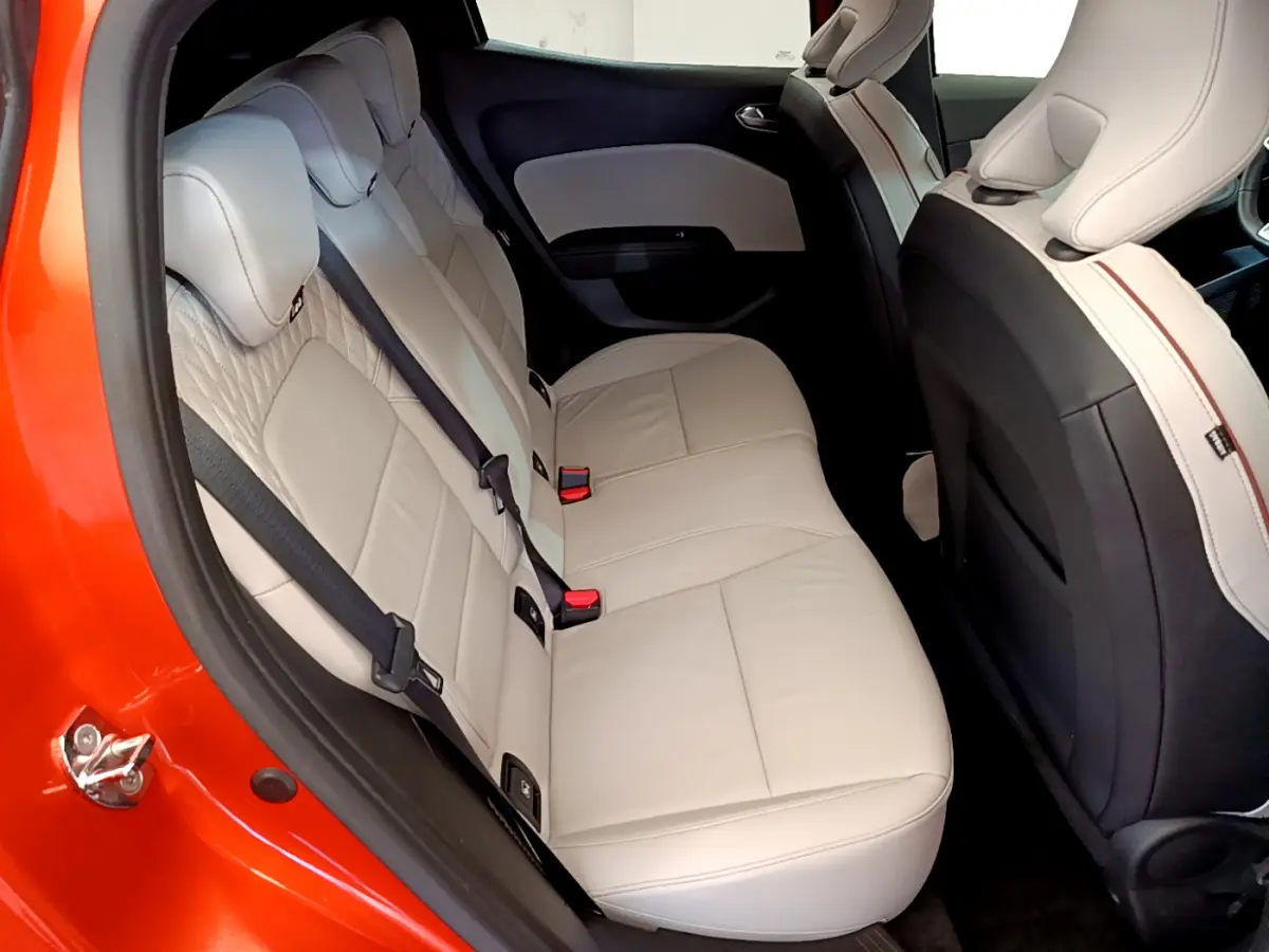 Vue intérieure côté gauche montrant la banquette arrière beige d'une Renault Clio orange 2021 Initiale Paris E-TECH.
