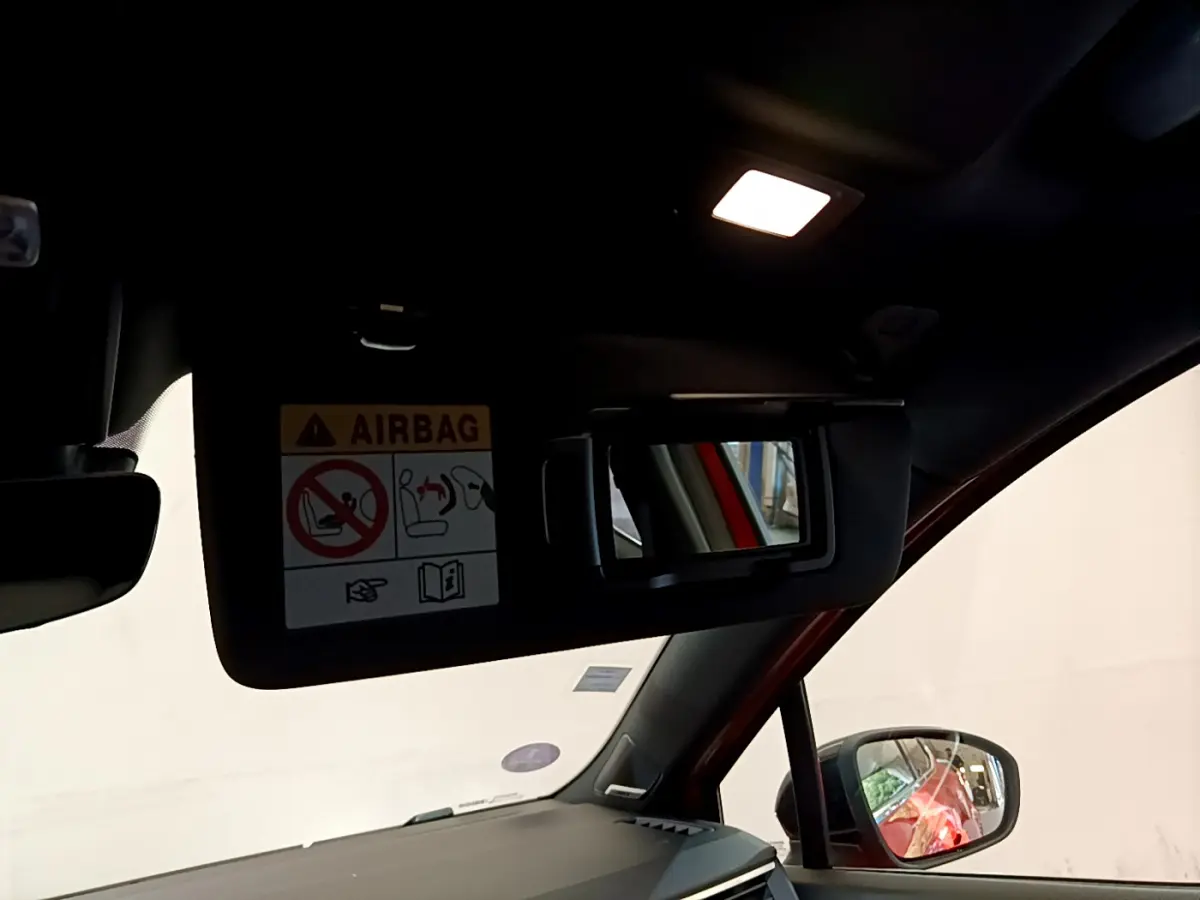 Détail du pare-soleil côté conducteur avec miroir et avertissement airbag dans Renault Clio Initiale Paris orange, vue intérieure avant.