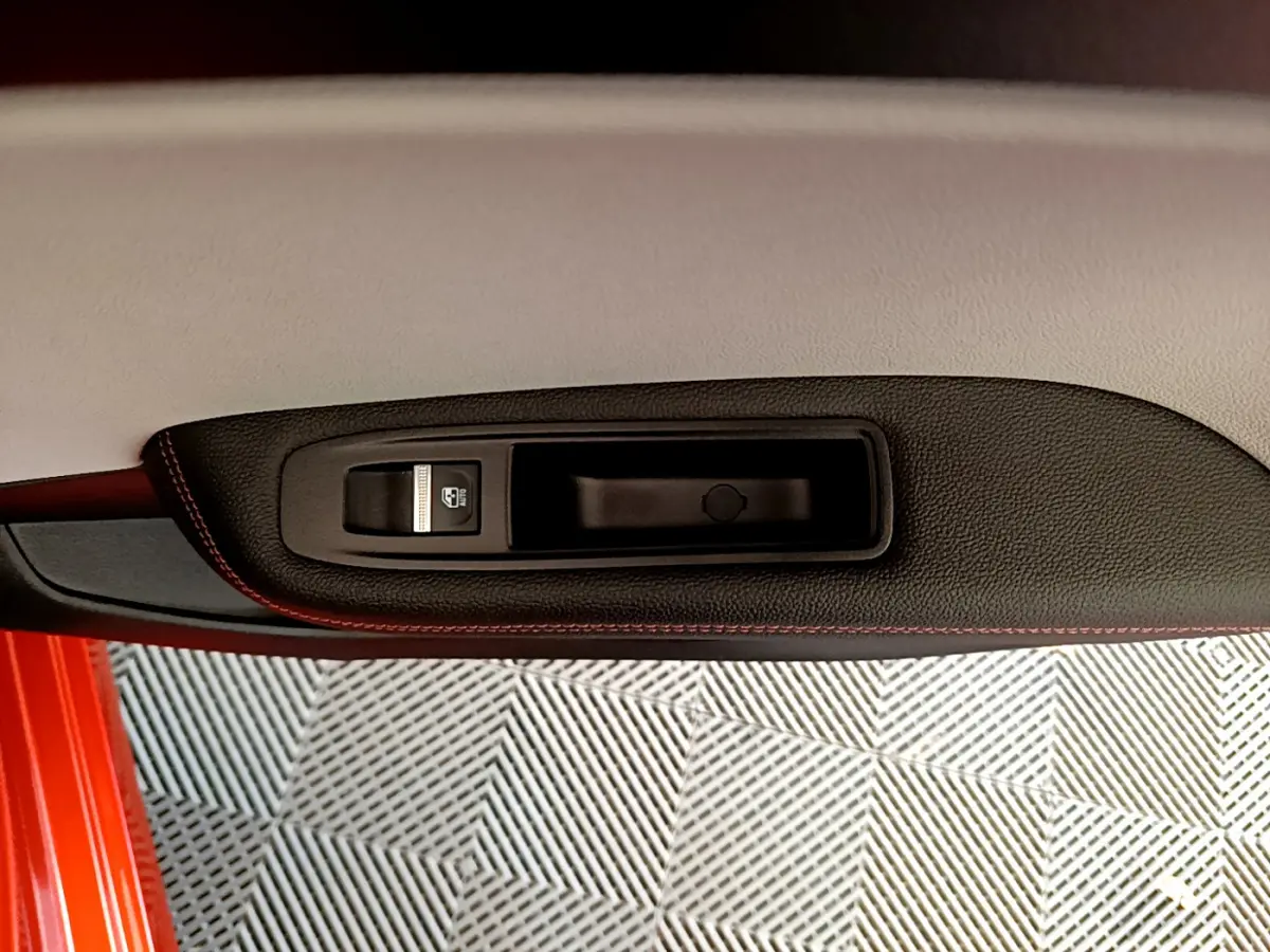 Gros plan sur la poignée intérieure côté gauche de la porte orange d'une Renault Clio Initiale Paris E-TECH 140 2021.