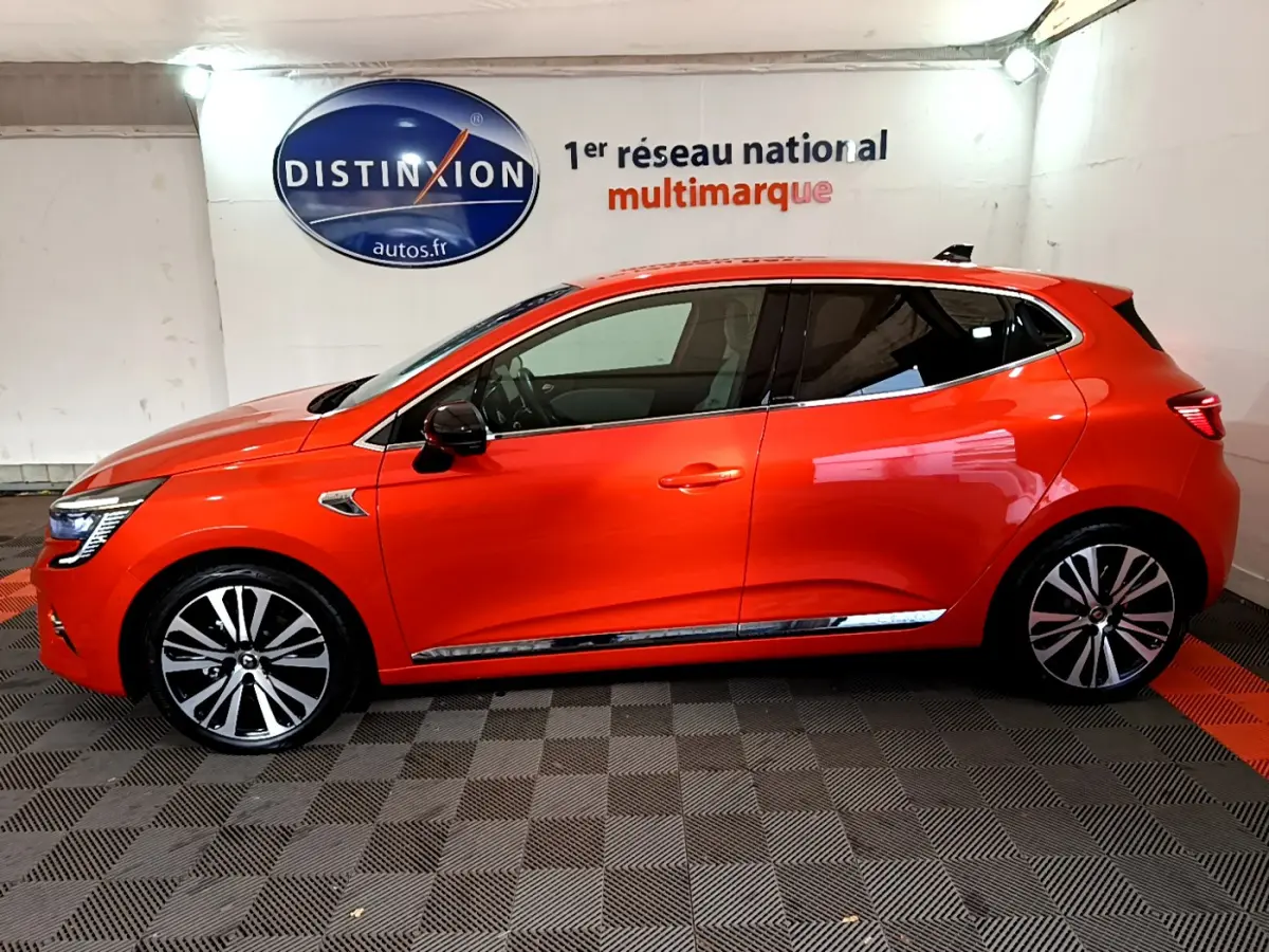 Profil côté gauche d'une Renault Clio Initiale Paris orange 2021 avec jantes alliage et rétroviseurs noirs brillants.
