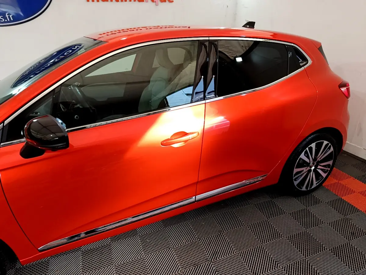 Profil côté gauche de la Renault Clio Initiale Paris orange 2021 avec jantes alliage et rétroviseur noir brillant.