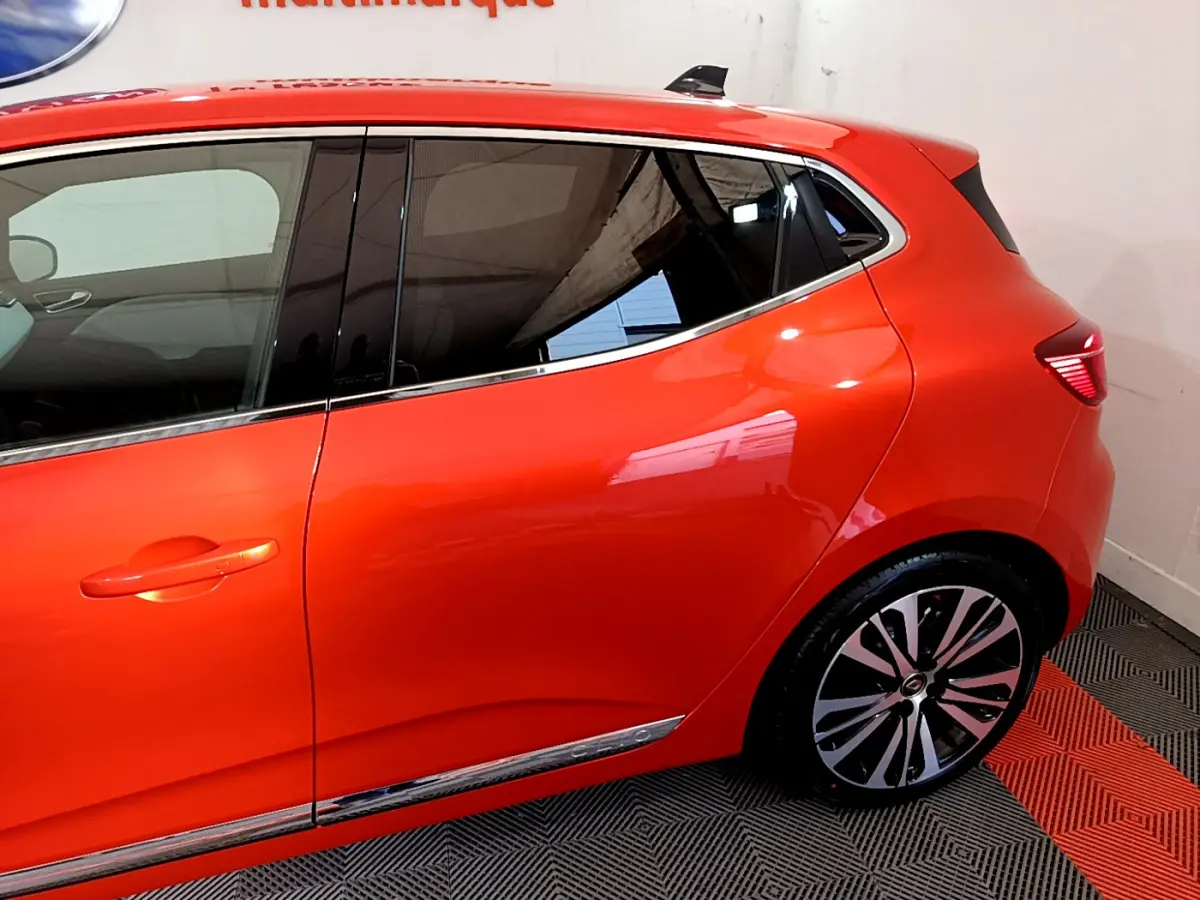 Vue latérale côté gauche d'une Renault Clio Initiale Paris orange avec jantes alliage et vitres teintées