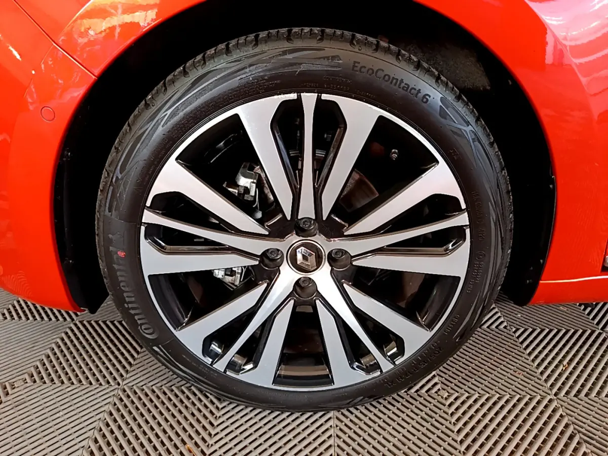 Gros plan sur la roue avant gauche de la Renault Clio Initiale Paris orange, jante alliage bicolore au design moderne.