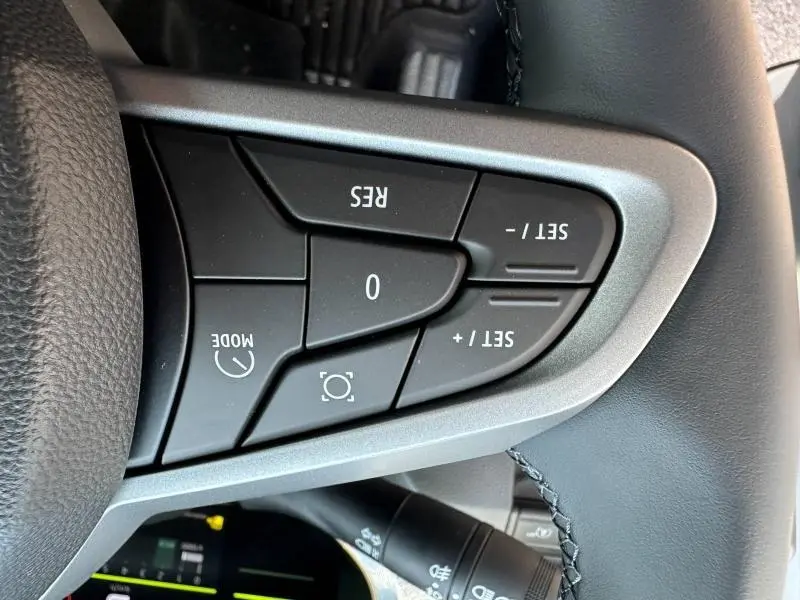 Gros plan sur les commandes de régulateur de vitesse au volant noir du Dacia Duster blanc 2025.