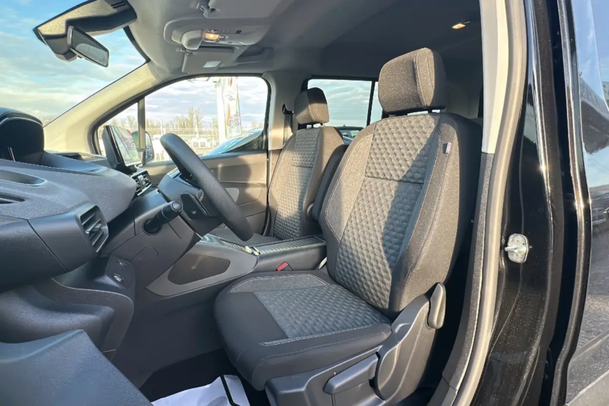 Vue intérieure côté conducteur du Peugeot Rifter 2025 noir perla nera, montrant les sièges tissu et le volant multifonctions cuir.