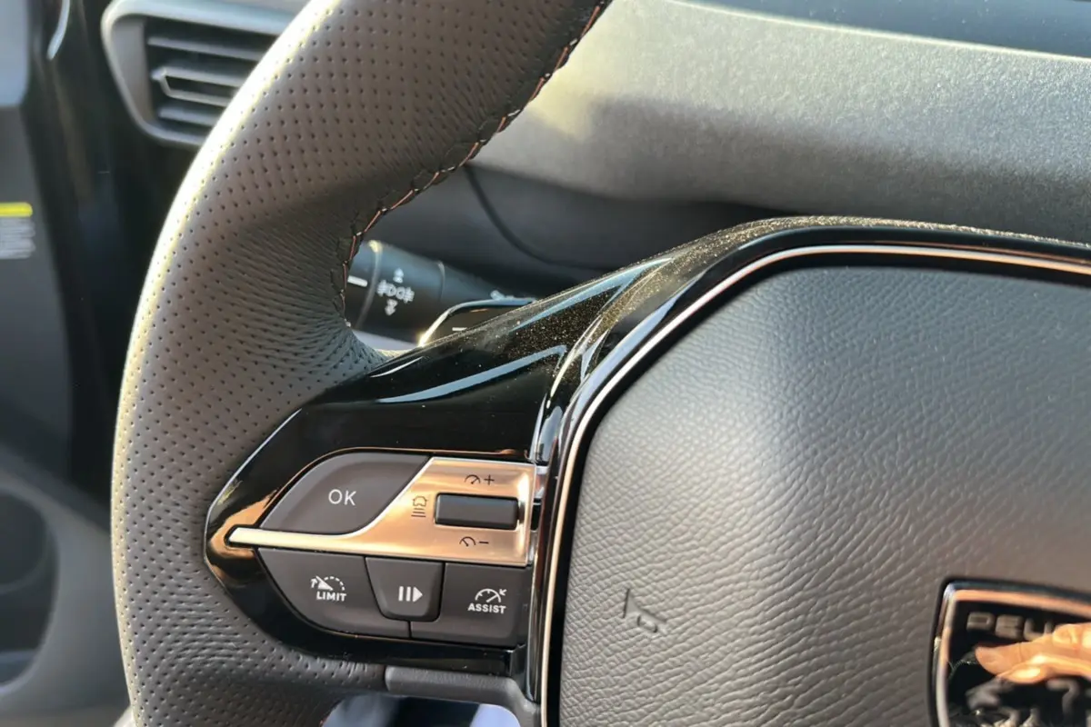 Gros plan sur le volant cuir perforé du Peugeot Rifter 2025 avec commandes multifonctions et finition noire brillante.