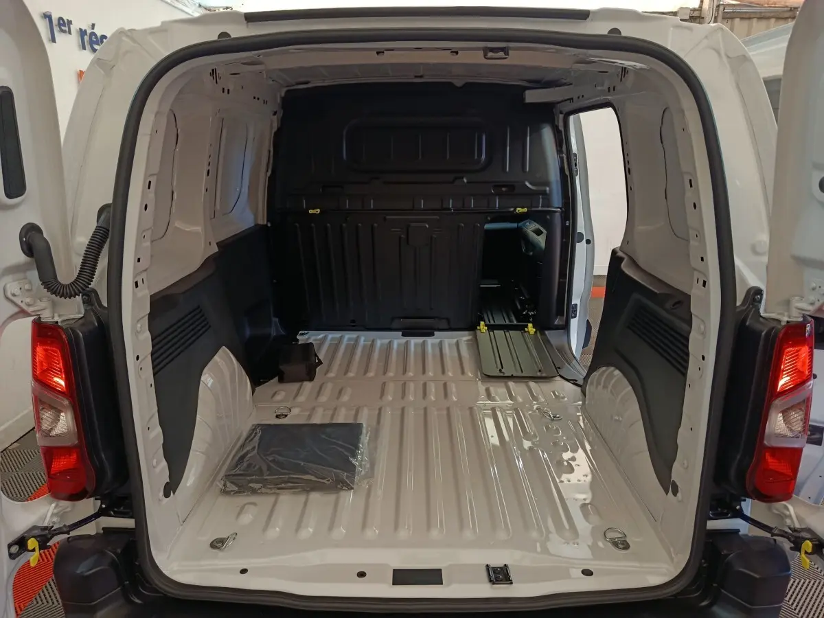Vue arrière du Peugeot Partner blanc 2026, montrant l'espace de chargement vide avec cloison pleine noire.