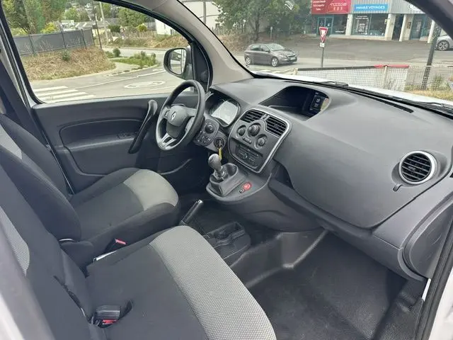 Vue intérieure côté conducteur du Renault Kangoo blanc 2020, montrant le tableau de bord et la console centrale avec boîte manuelle.