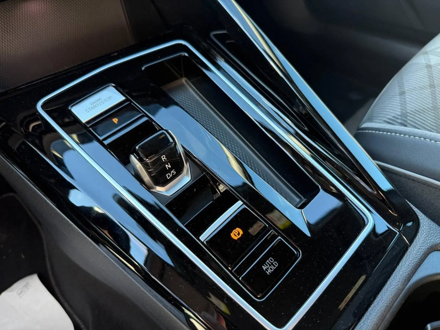 Vue en plongée sur la console centrale noire brillante avec levier de vitesses et bouton start/stop de la Volkswagen Golf 2024.