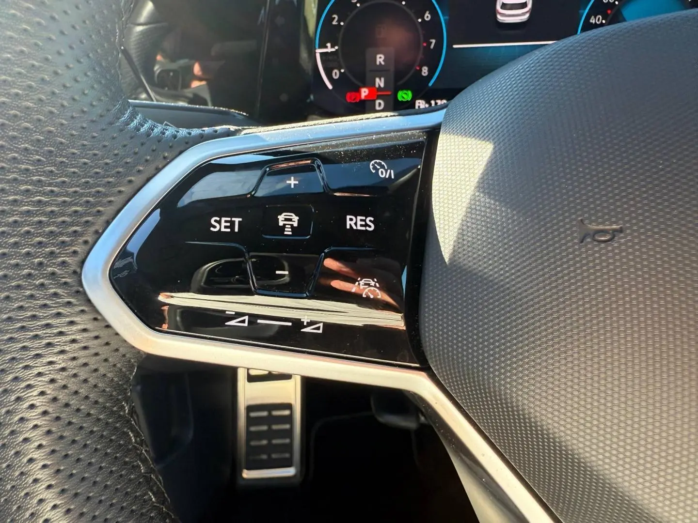 Gros plan sur la partie gauche du volant cuir perforé de la Volkswagen Golf 2024 avec commandes de régulateur de vitesse.