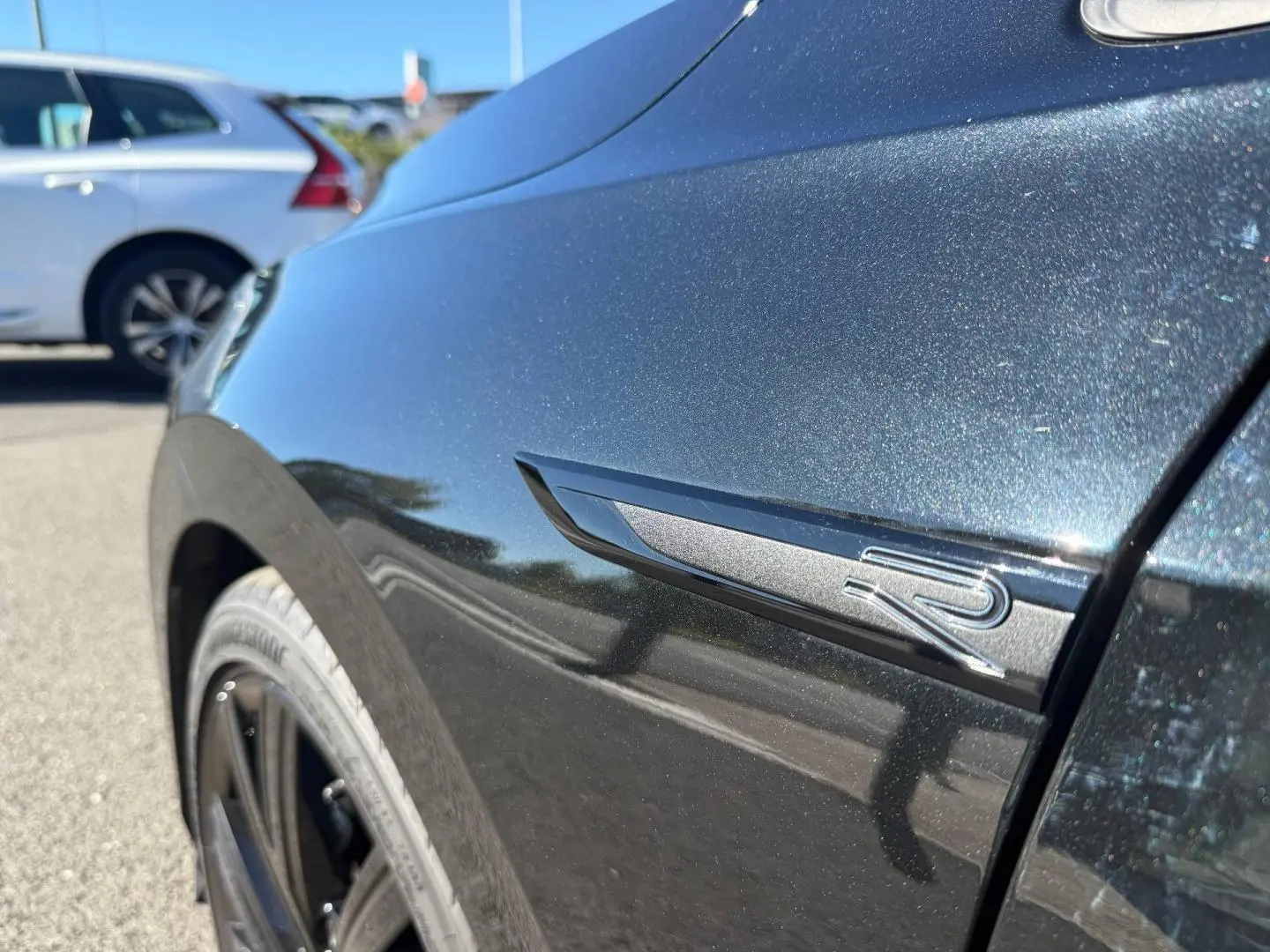 Gros plan sur l'aile avant droite noire métallisée Grenadilla avec logo R de la Volkswagen Golf 2024.