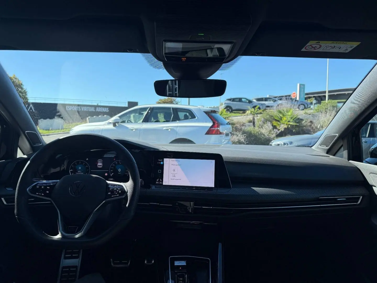 Vue intérieure avant de la Volkswagen Golf noire, avec volant multifonction et écran tactile central lumineux.