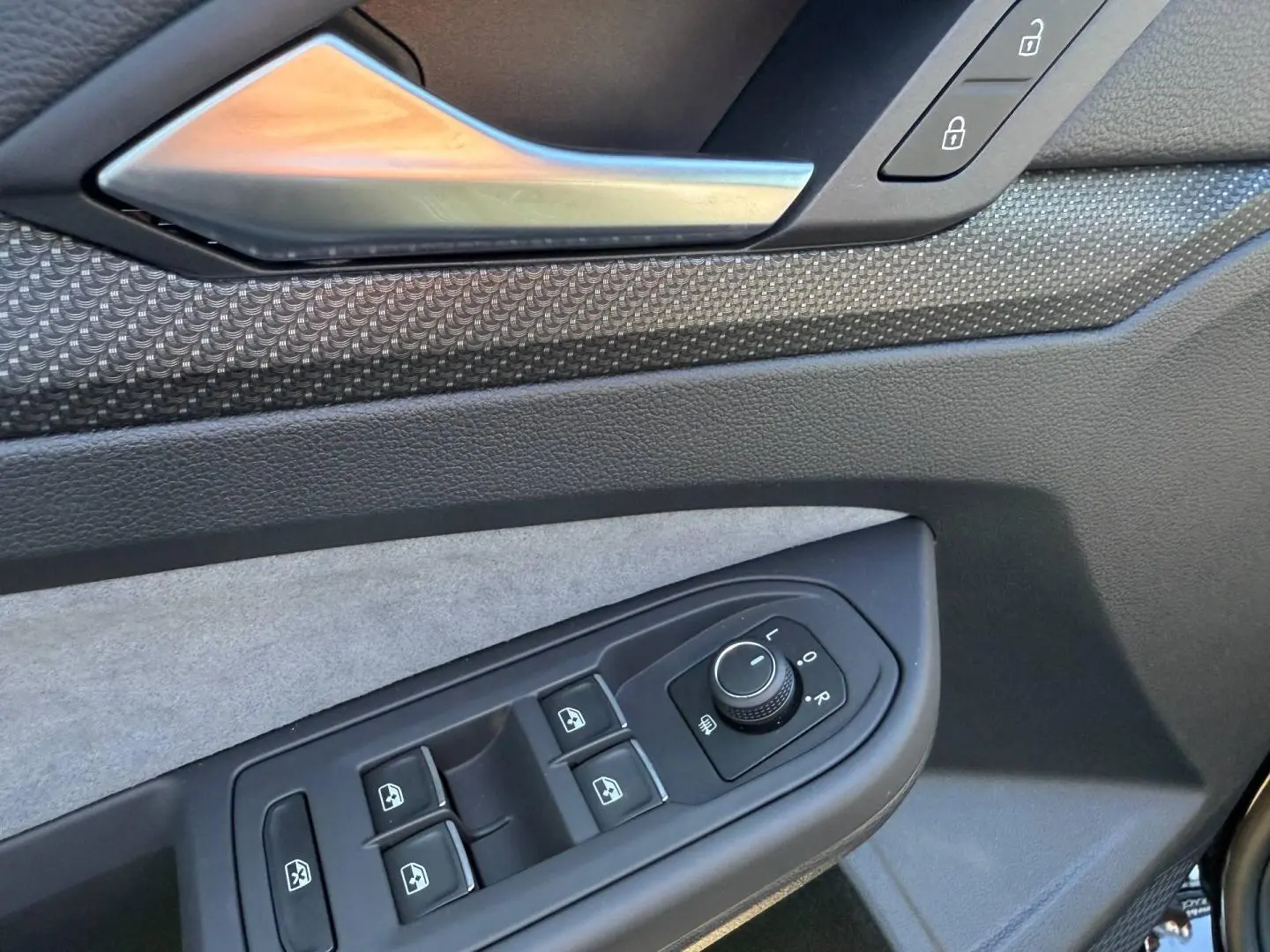 Détail de la porte avant gauche de la Volkswagen Golf 2024 noir Grenadilla, avec commandes des vitres et rétroviseurs.