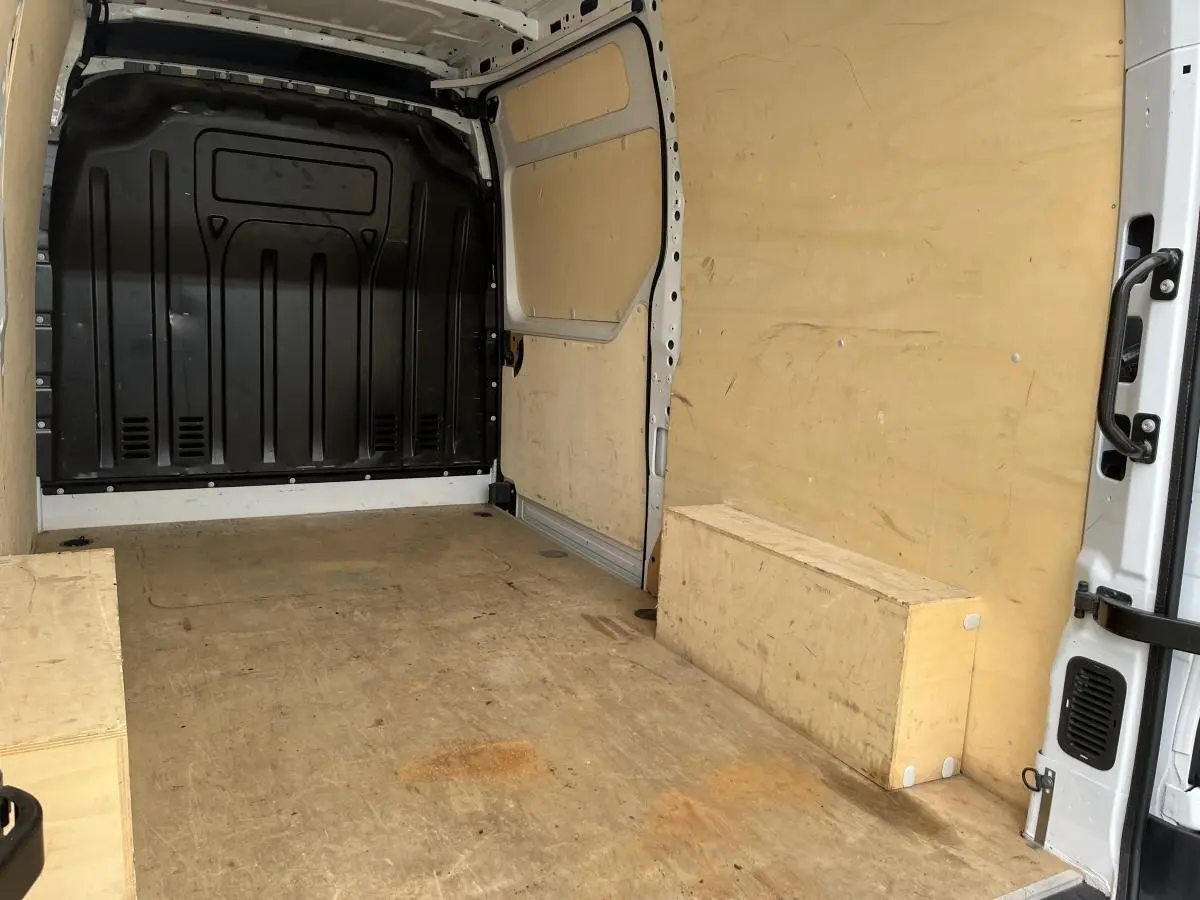 Intérieur du coffre du Renault Master blanc, vue depuis l'arrière droit, avec plancher et parois en bois clair.