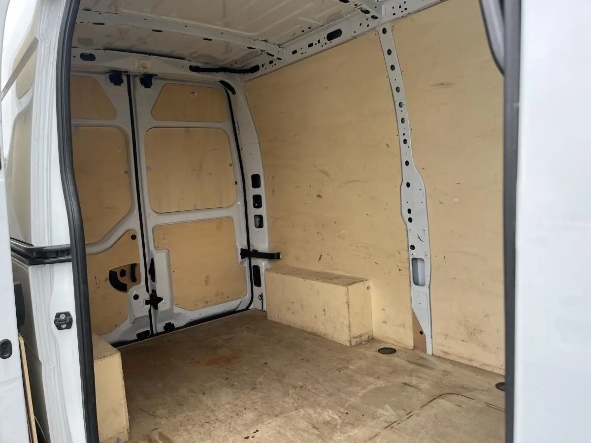 Vue intérieure arrière du Renault Master blanc 2022 avec aménagement bois complet et anneaux d'arrimage visibles.