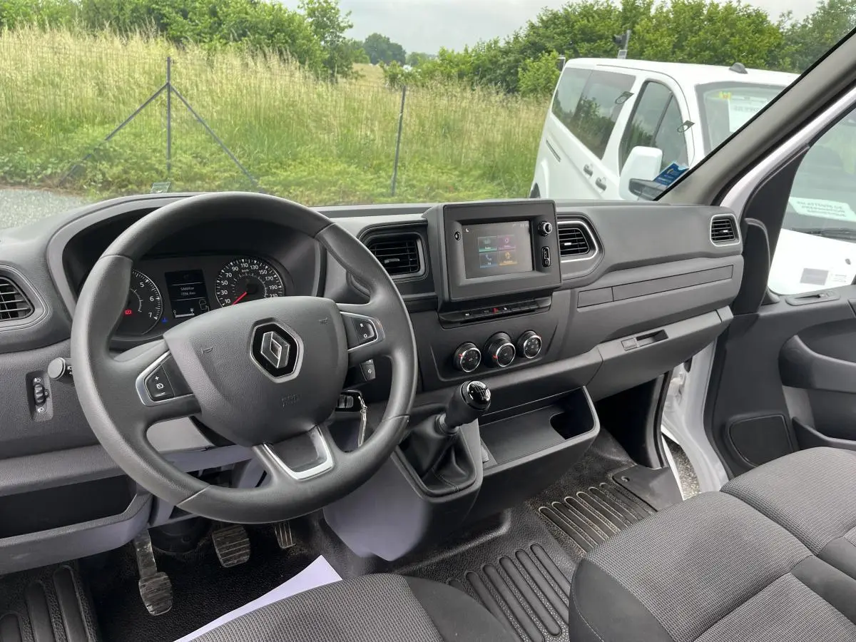 Intérieur du Renault Master 2022 vu côté conducteur, tableau de bord noir avec volant et banquette tissu gris.
