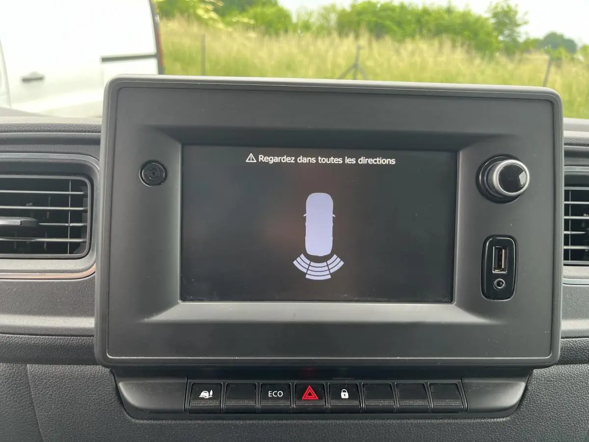 Écran central du tableau de bord du Renault Master blanc 2022 affichant l'alerte de détection d'obstacle arrière.