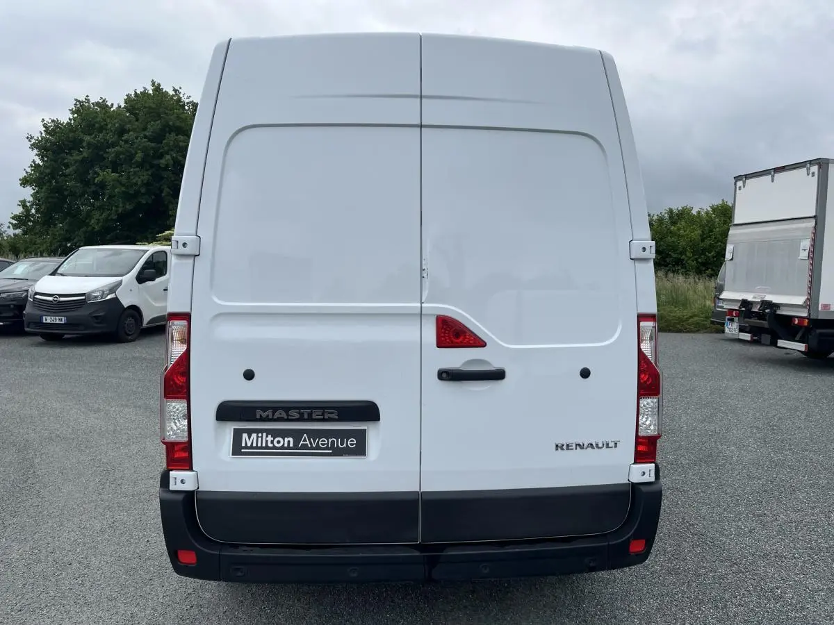 Vue arrière d'un Renault Master blanc avec portes arrière tôlées et logo visible sur un parking.