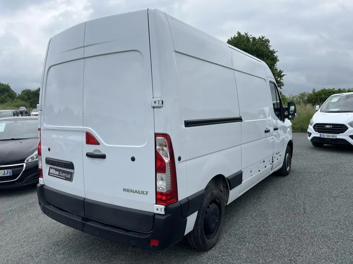 Renault Master blanc en vue 3/4 arrière droit, fourgon utilitaire avec portes arrière tôlées et jantes tôles noires.