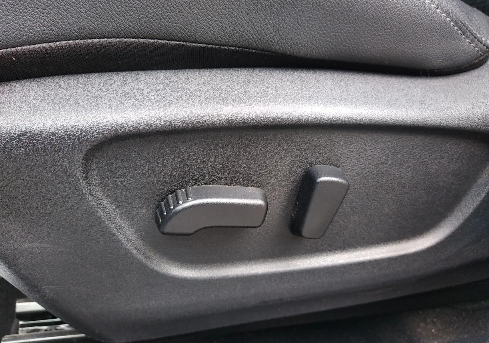 Détail des commandes de réglage électrique du siège conducteur noir dans un Nissan Qashqai blanc 2018.