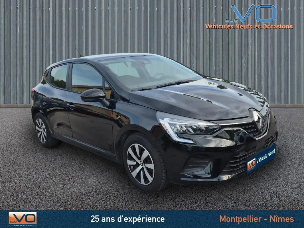 Renault Clio V TCe 90 Equilibre noire vue en 3/4 avant droit sur sol gris devant un mur métallique.