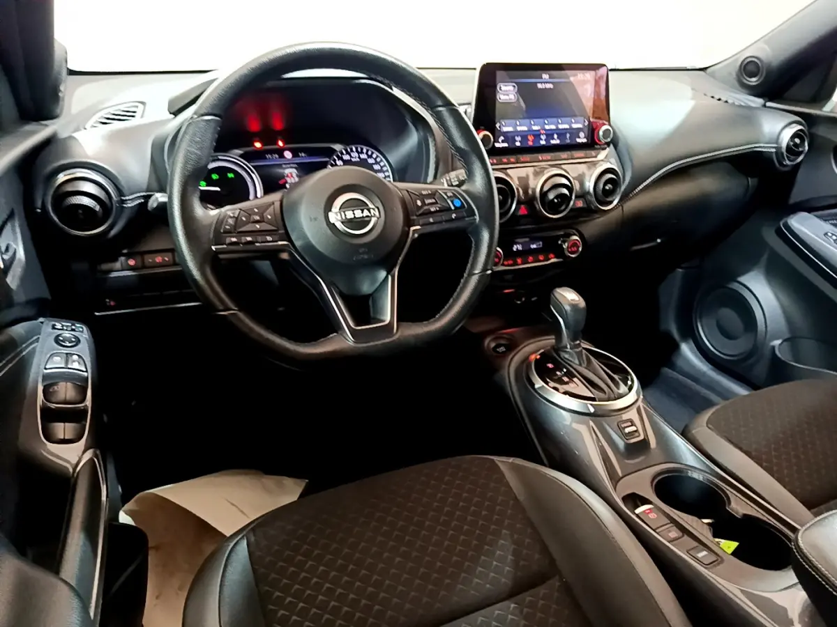 Intérieur du Nissan Juke Hybrid 143 Business+ 2023, vue cockpit côté conducteur, tableau de bord et console centrale noirs.